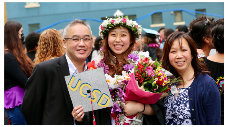 Student taking a picture with their parents on graduation day in their cap and gown